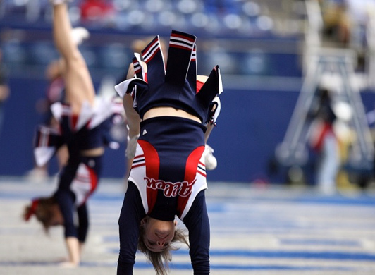 Cheerleader performs summersault in gym